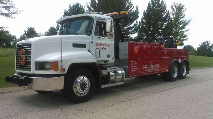 A white and red tow truck is parked on the side of the road.