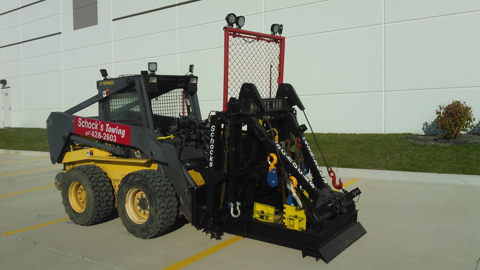 A yellow and black skid steer is parked in a parking lot.