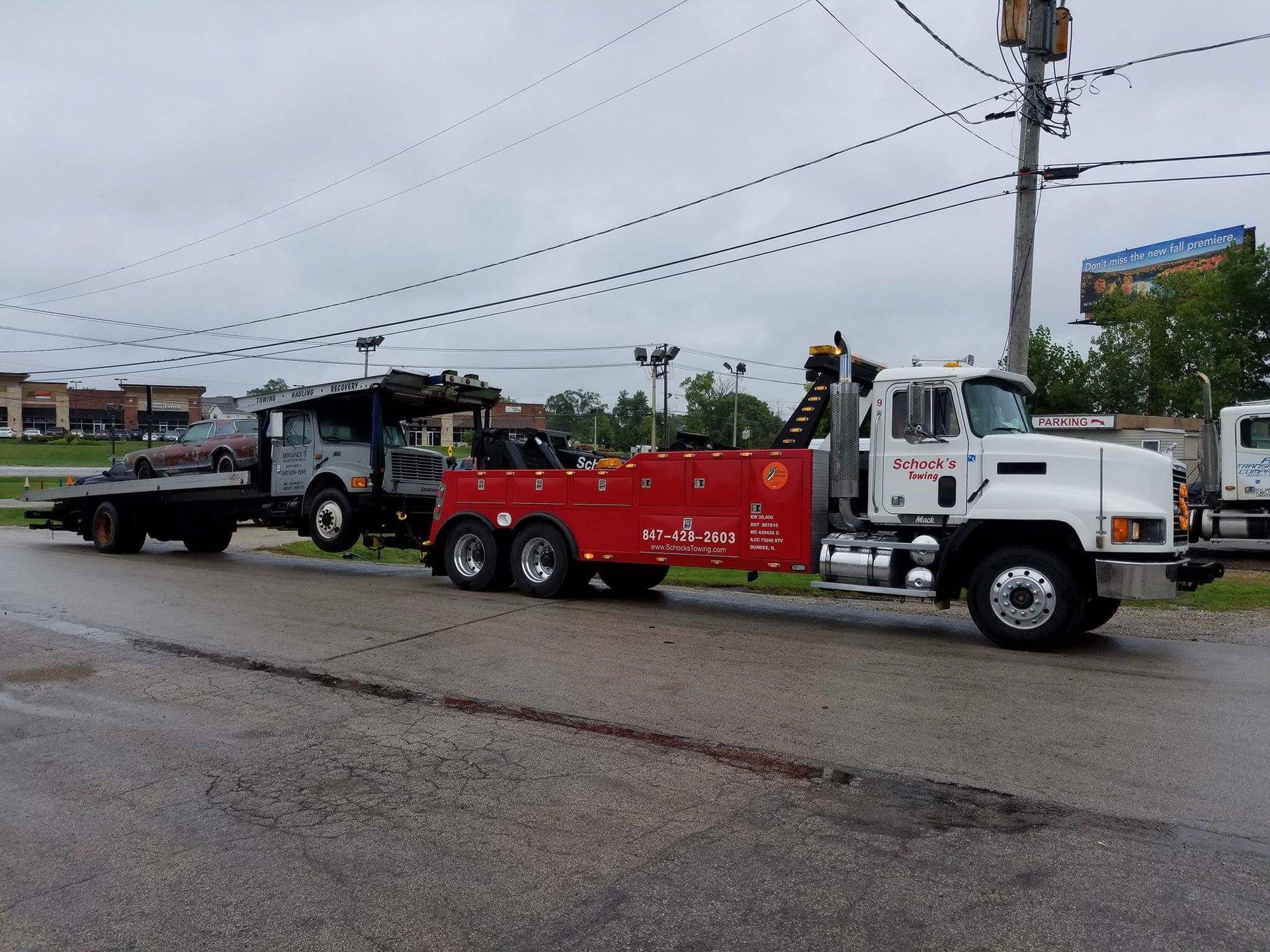 Two tow trucks are parked on the side of the road.