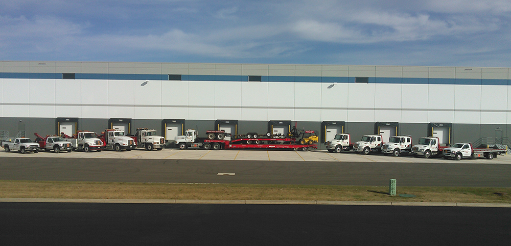 A row of trucks are parked in front of a large building.