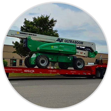 a green lift is sitting on top of a red trailer .