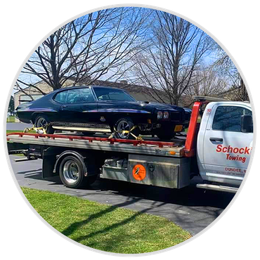a black car is being towed by a tow truck .