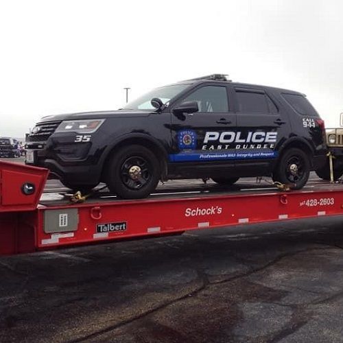 a police car is sitting on top of a red trailer .