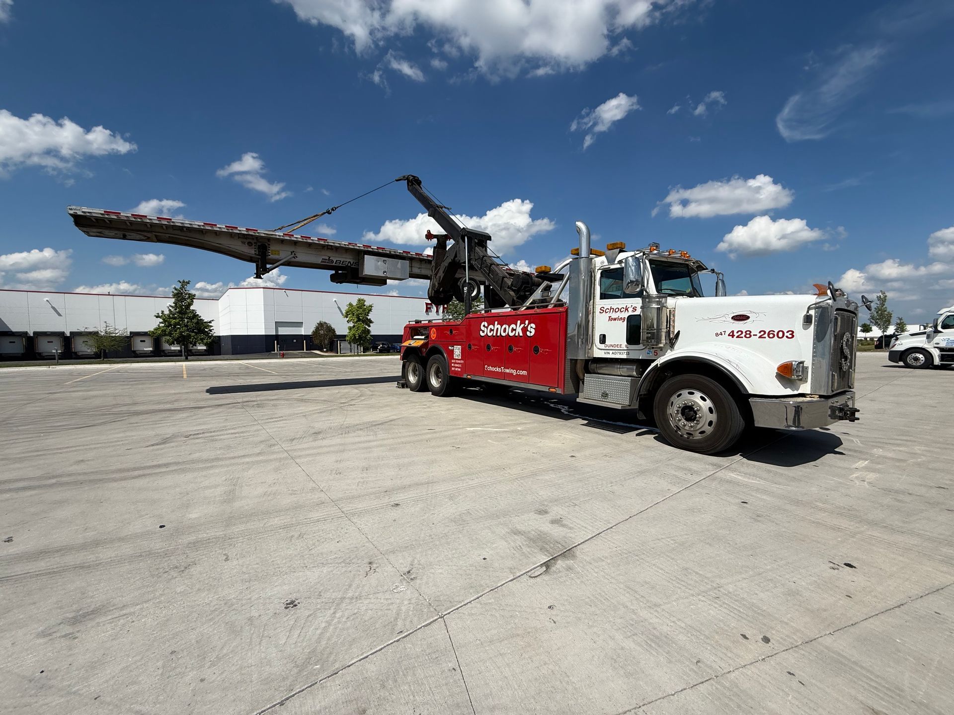 A red and white tow truck in a parking lot