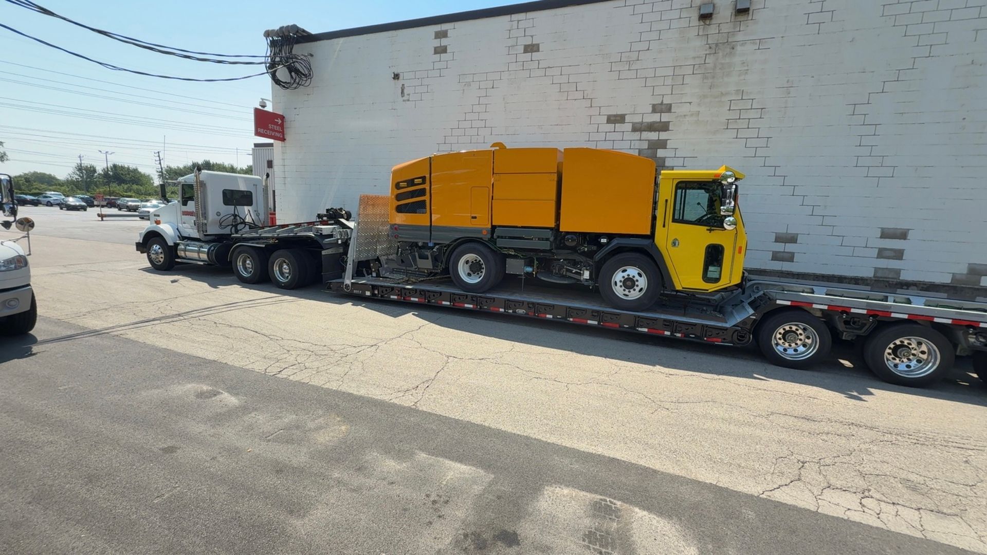 A yellow truck is sitting on a trailer in front of a building.