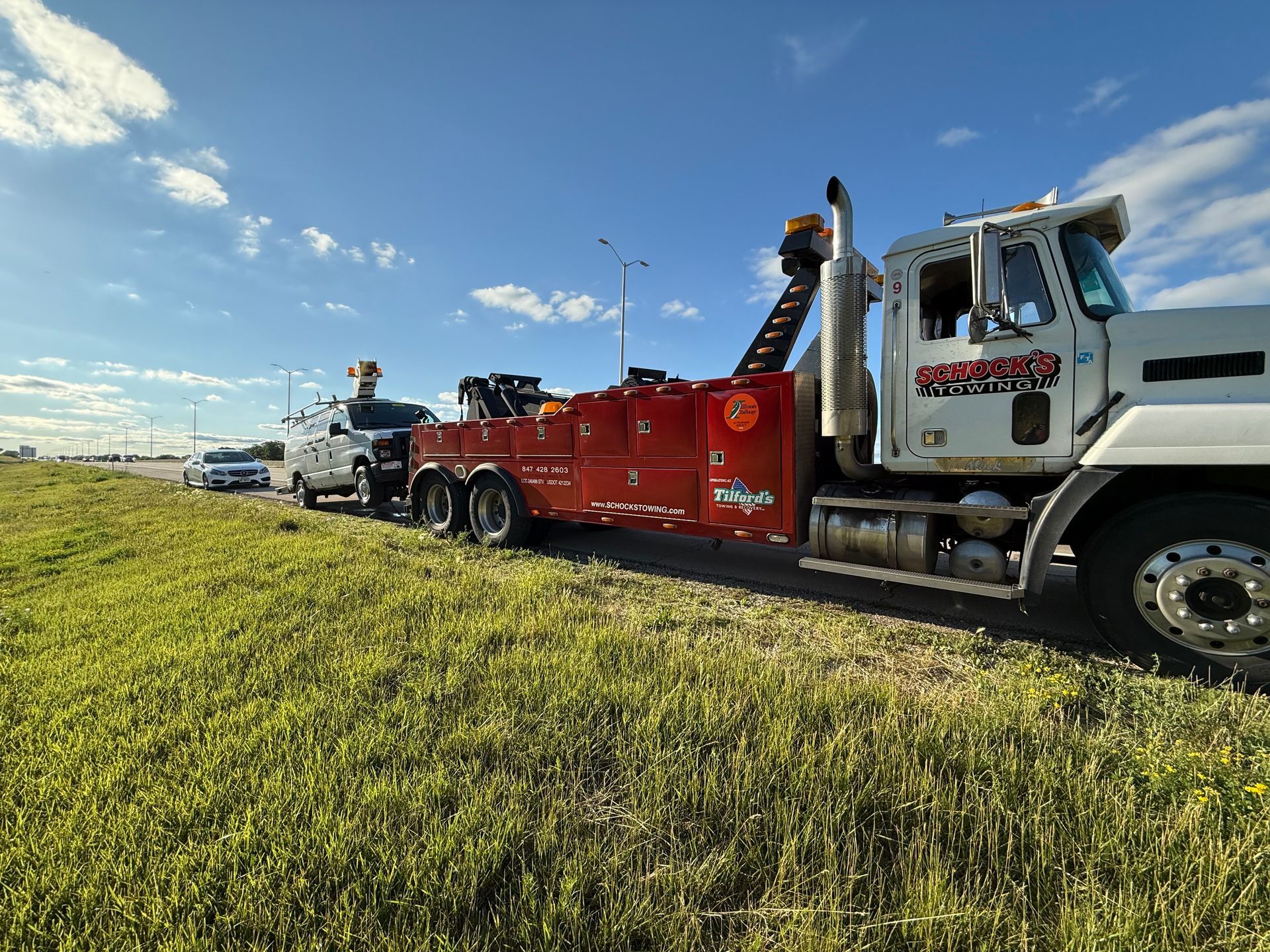 A tow truck is towing a car on the side of the road.