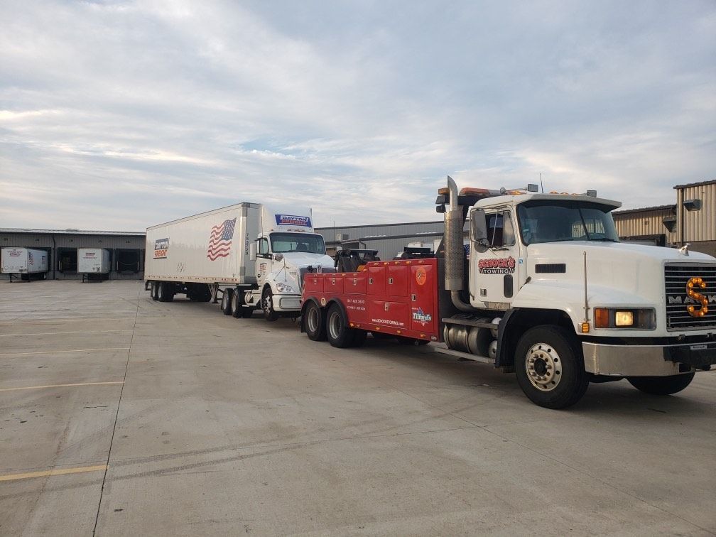 Heavy-duty tow truck assisting a semi-truck on a highway in Elgin, IL