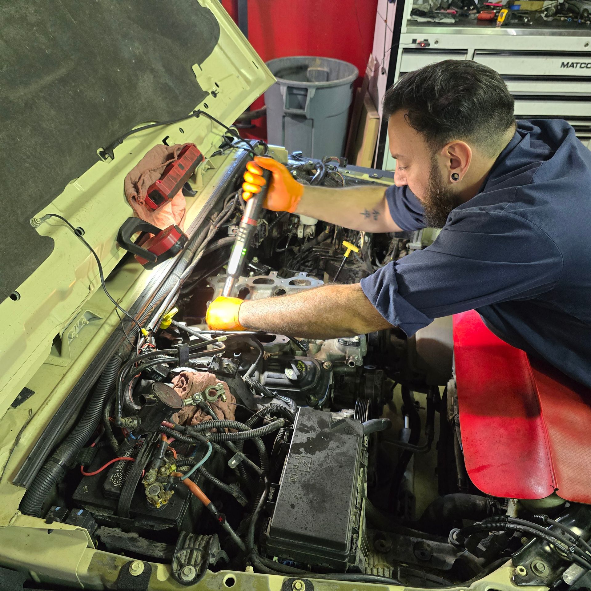Mechanic working on car engine, using a wrench in a garage.