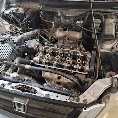 Car engine with exposed cylinder head, open hood, and air intake.