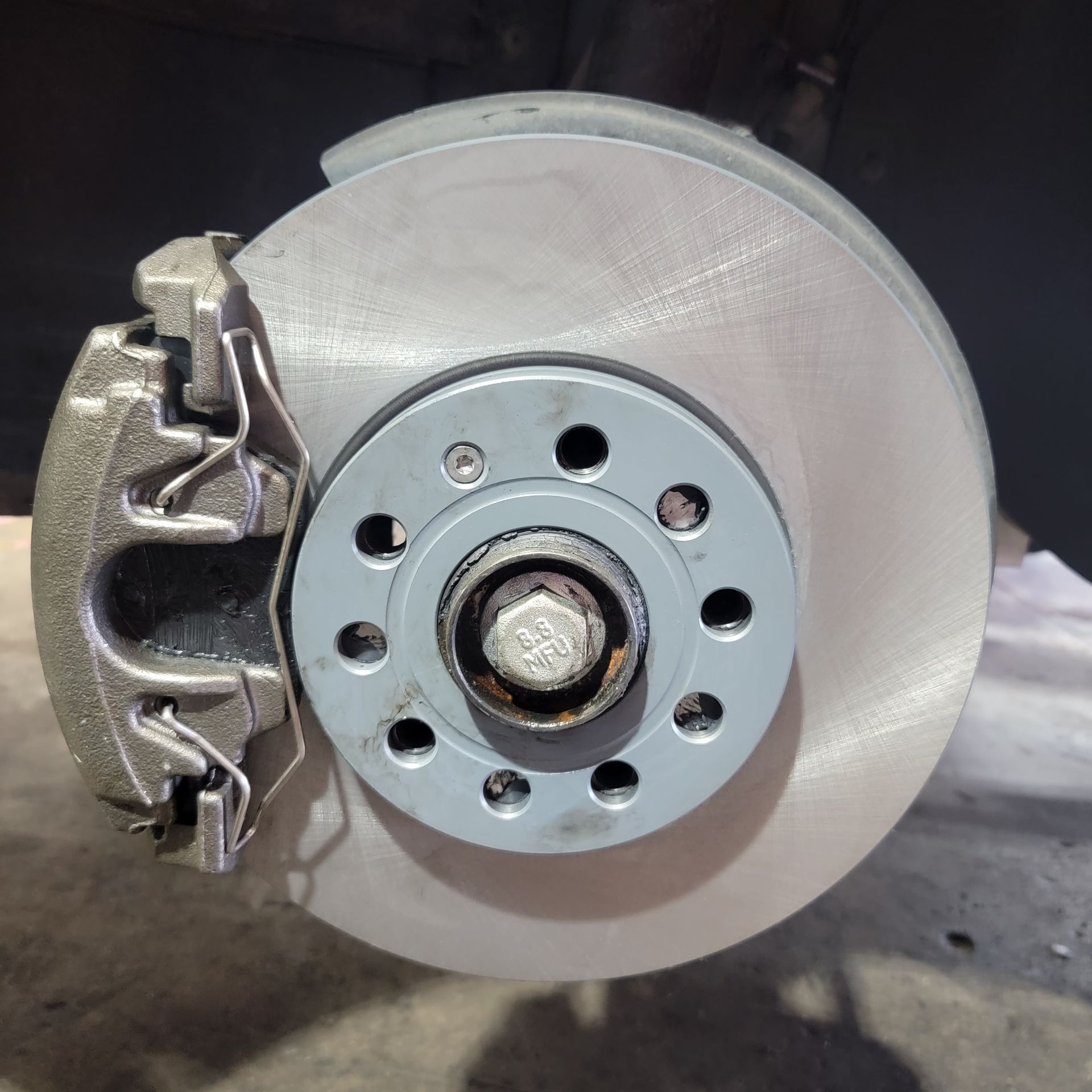 A car brake disc assembly with a gray caliper and rotor, viewed close up.