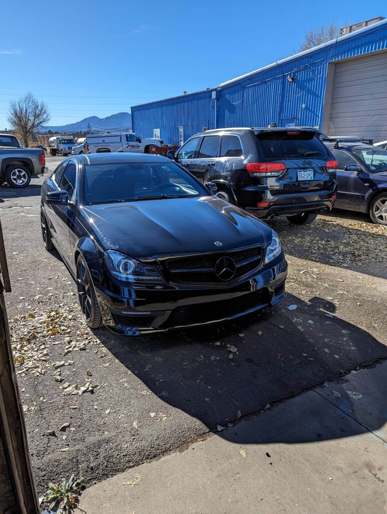 Black Mercedes coupe parked outside a building on a sunny day.