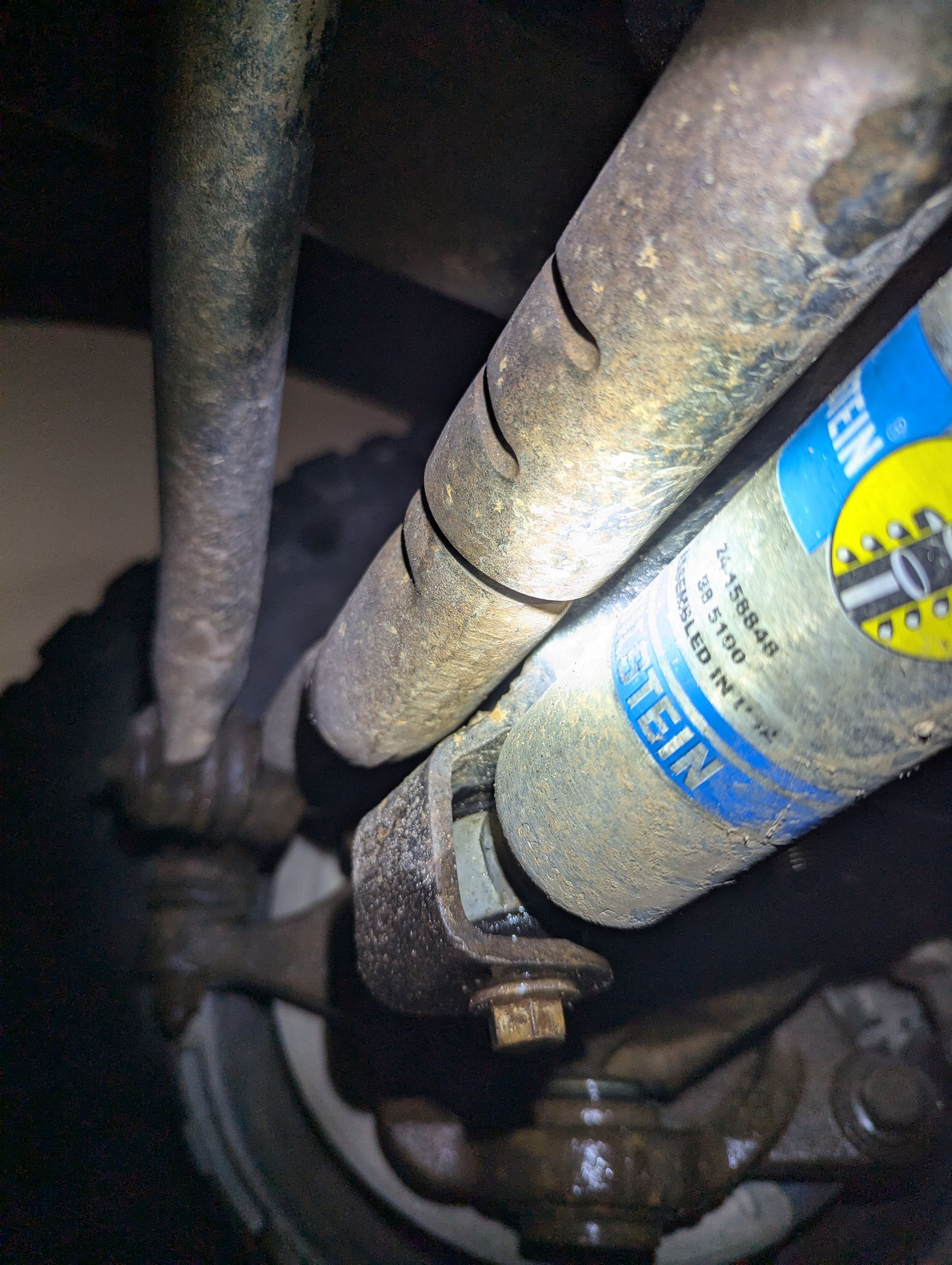 Suspension components of a vehicle, including a Bilstein shock absorber, coated in dust.
