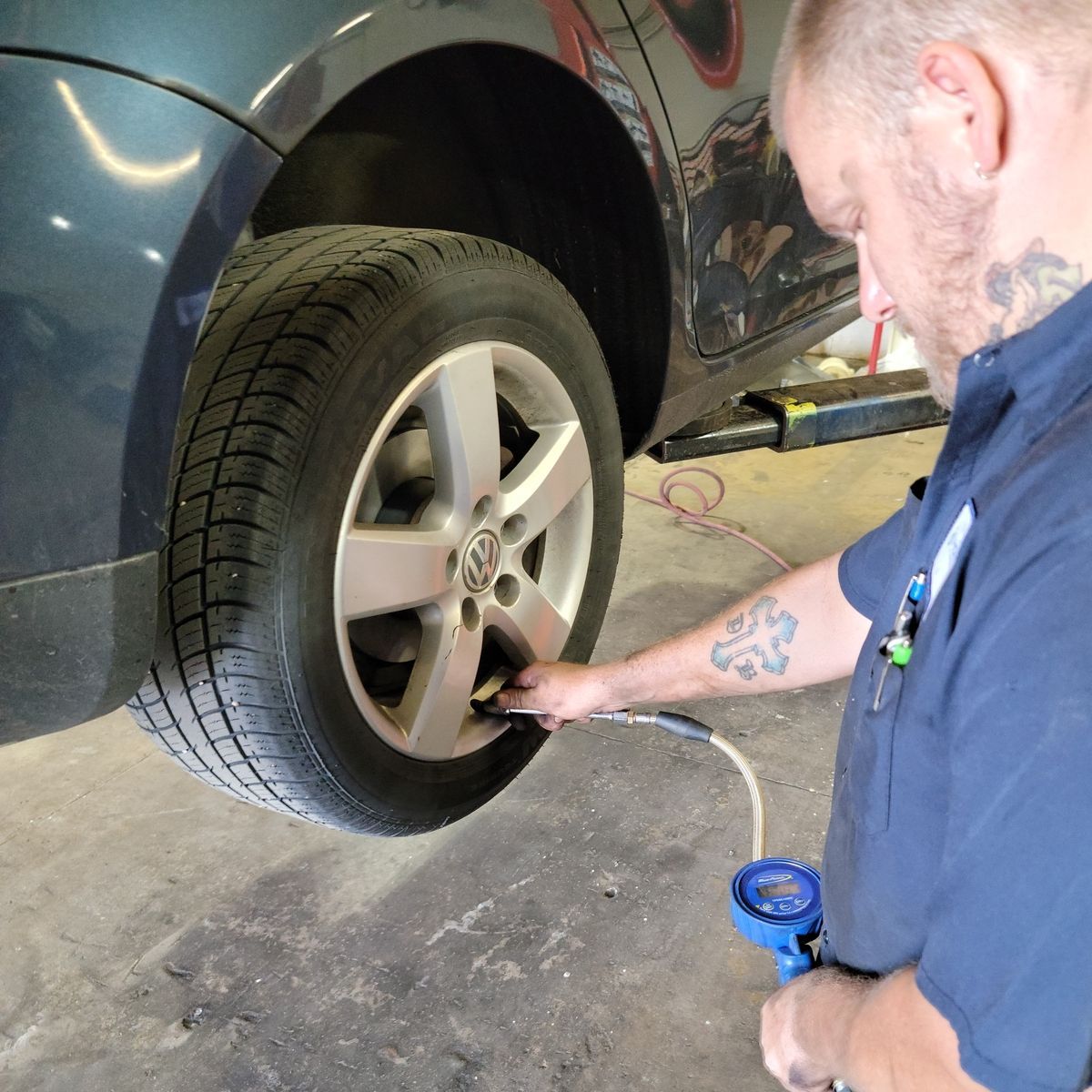 Mechanic inflating a car tire in a garage.