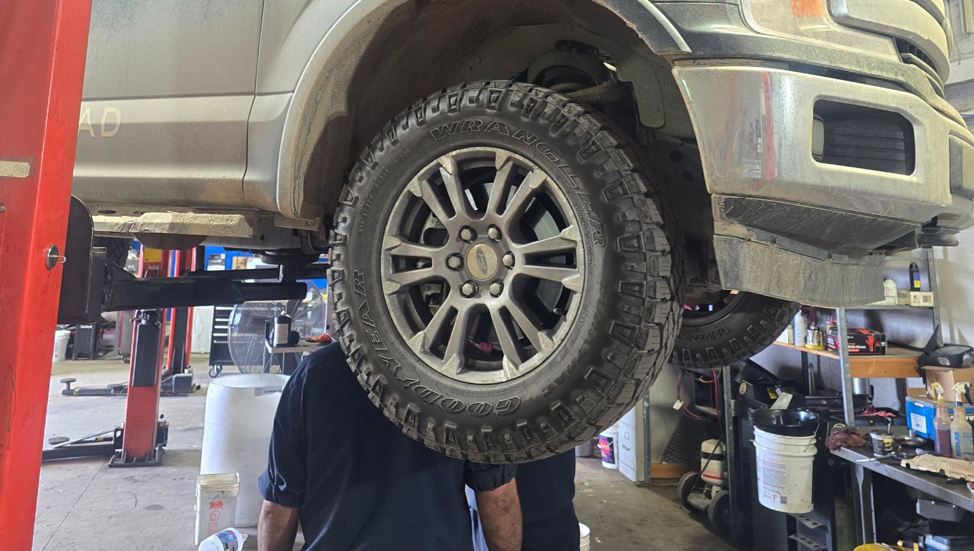 A mechanic working under a truck raised on a lift in a repair shop.