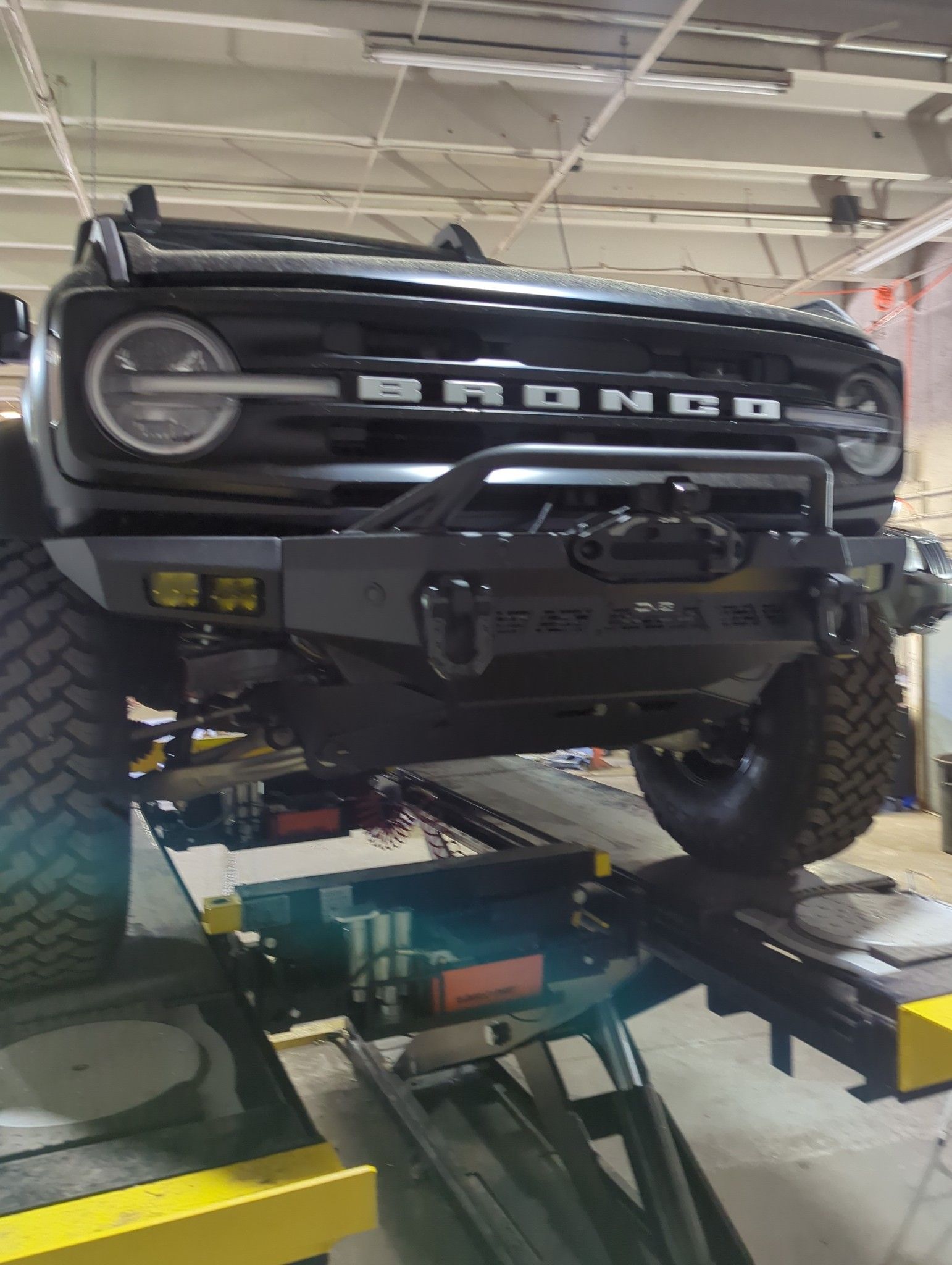 Black Ford Bronco SUV on a lift in a garage.