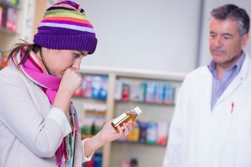 Patient smelling medicine while pharmacist watches in a pharmacy