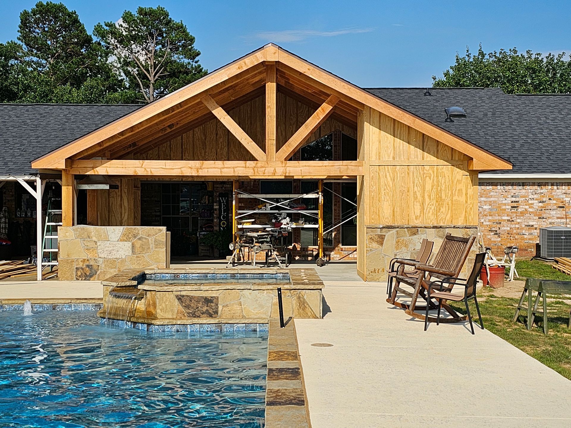 Poolside structure under construction with exposed wooden beams and a new roof.