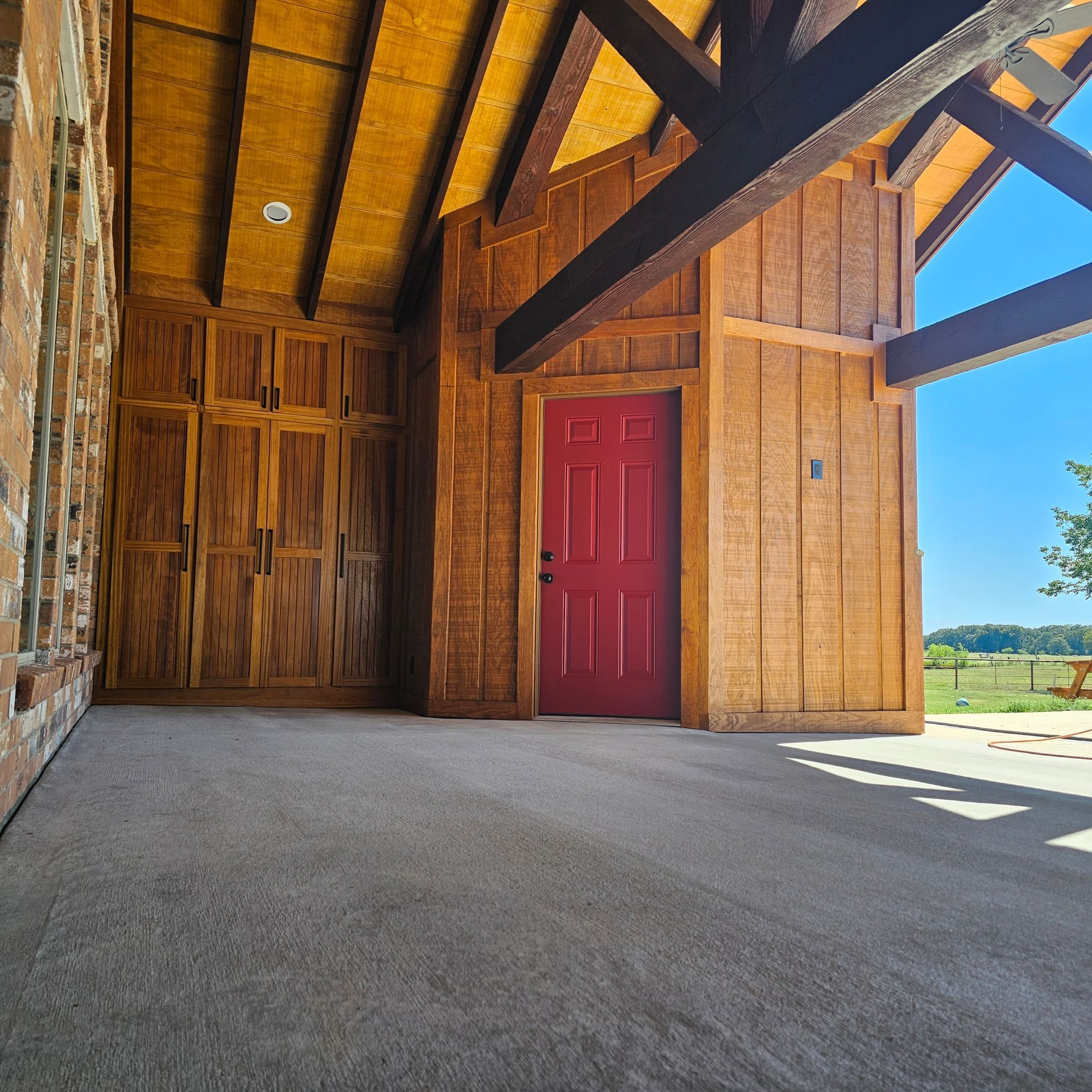 Wooden building exterior with red door and exposed beams, sunny day.