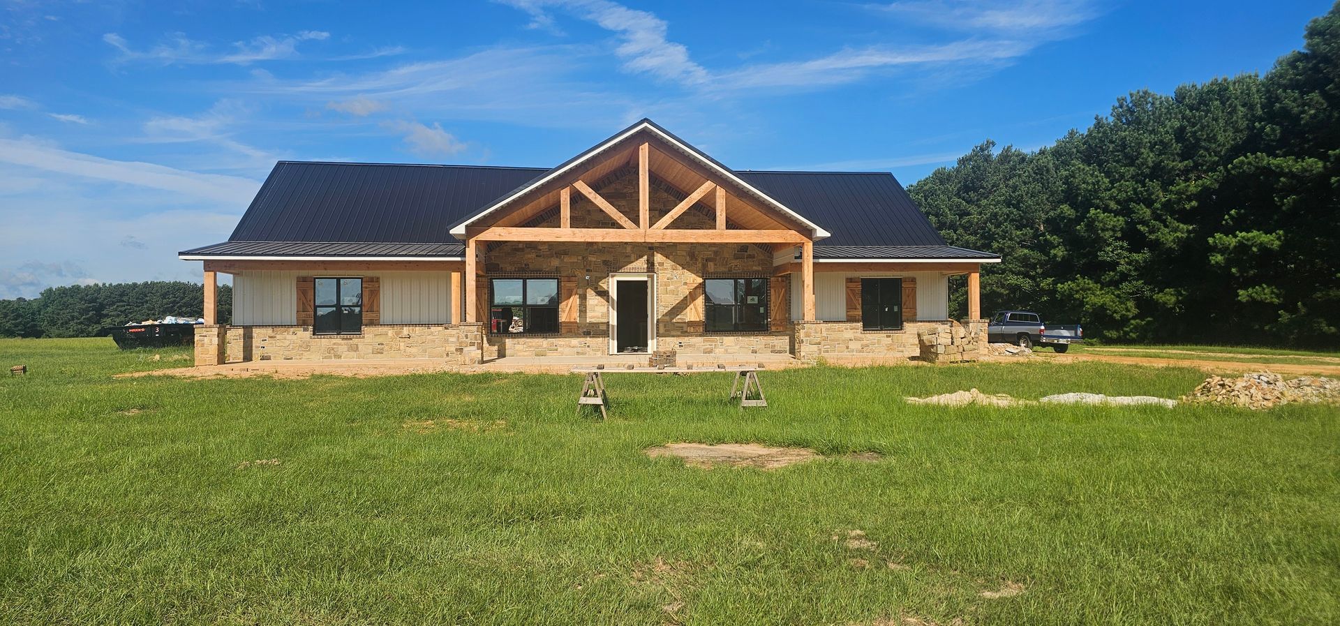 A newly constructed house with a wooden entryway, a dark roof, and a grassy lawn under a blue sky.