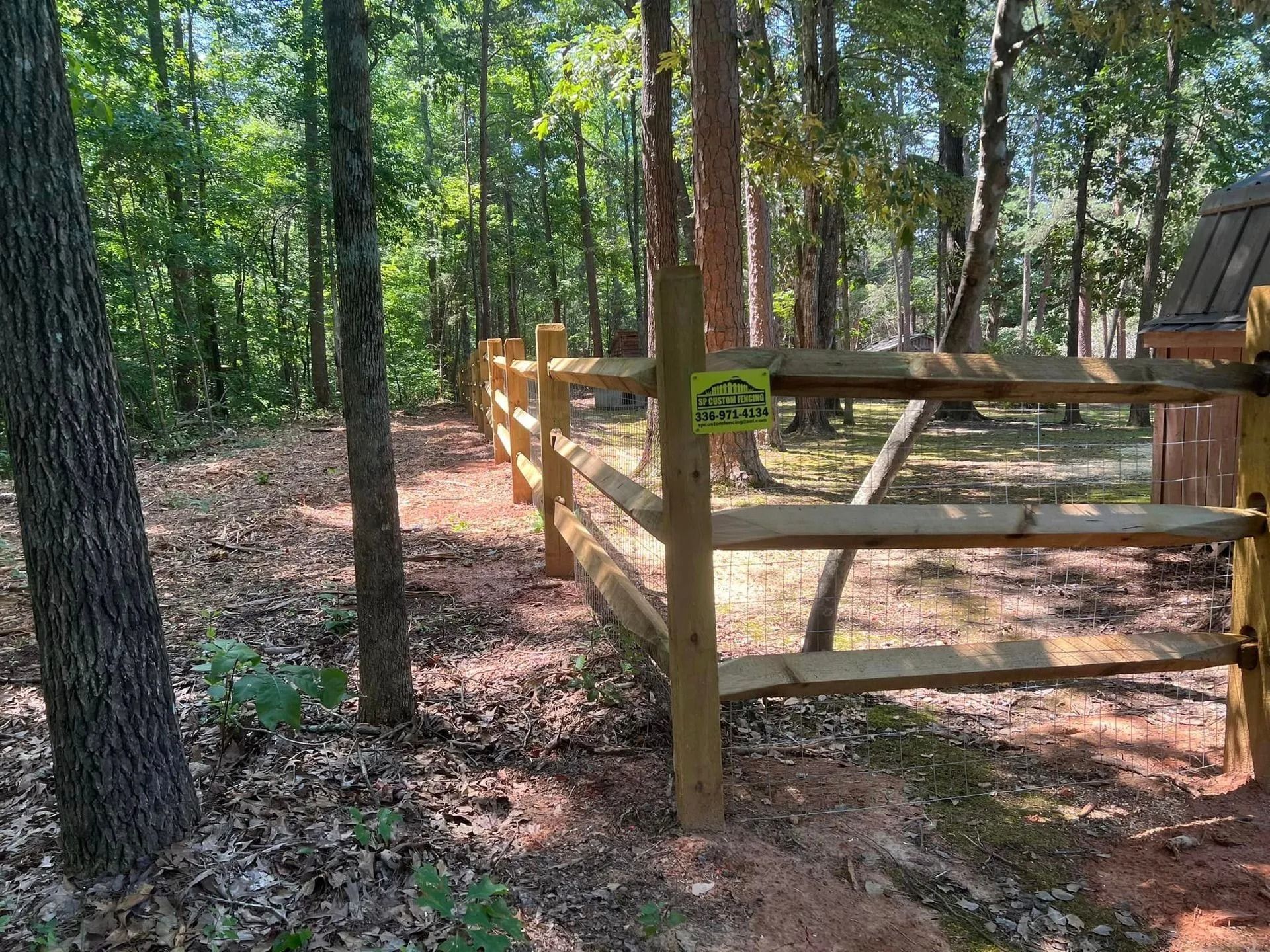 Wooden fence along a forest path, trees in background, sunny day.