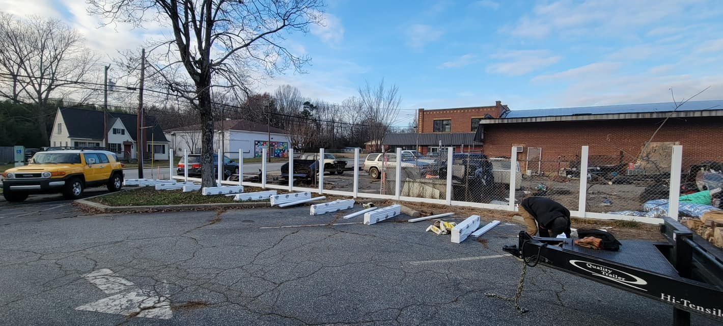 A fence being assembled outdoors on a cloudy day, with a yellow car in the background.