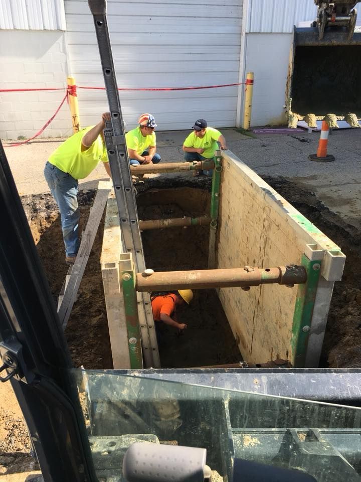A group of construction workers are working in a trench.
