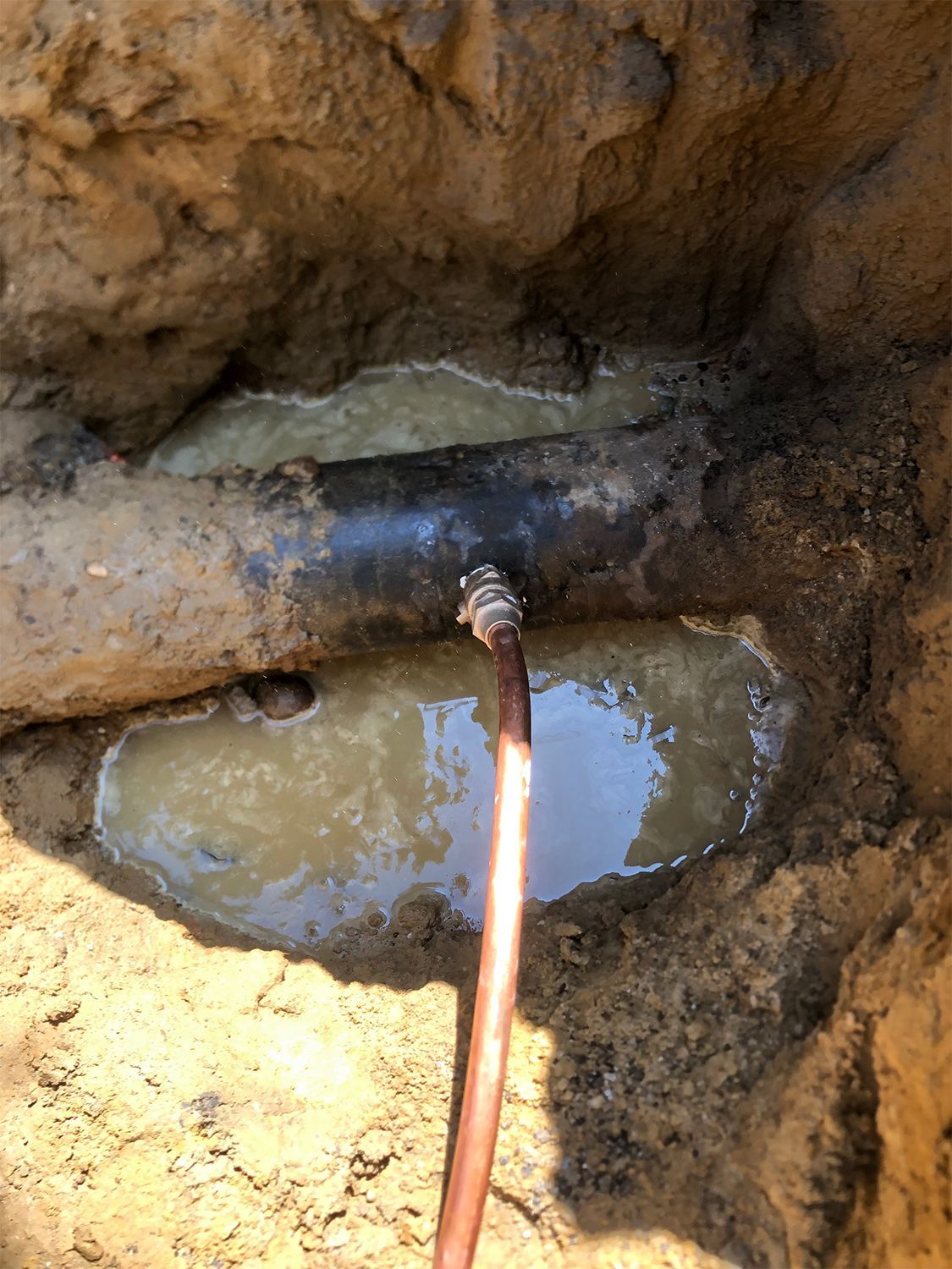 A copper pipe is sticking out of a hole in the ground.
