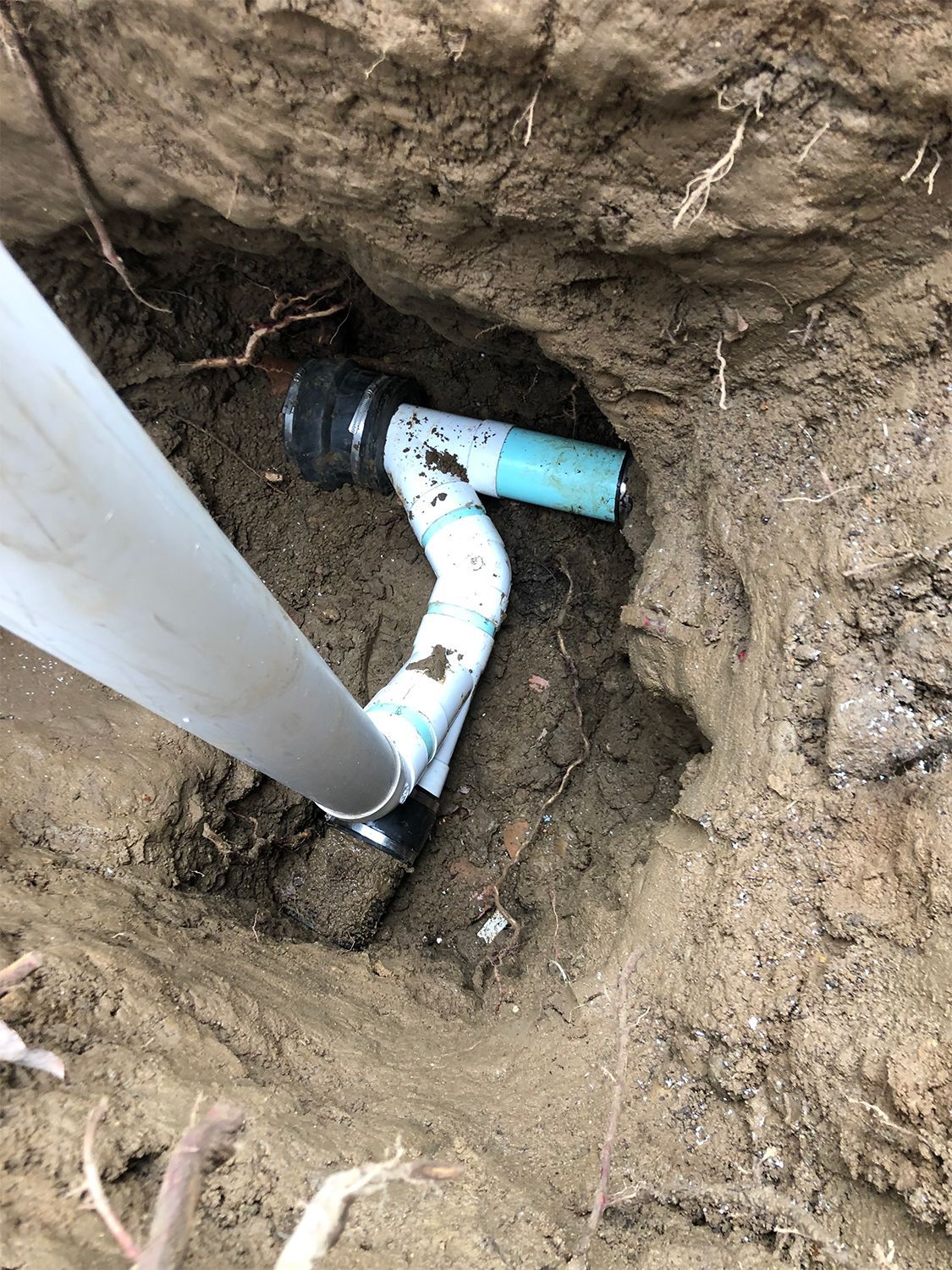 A pipe is laying in the dirt next to a pole.