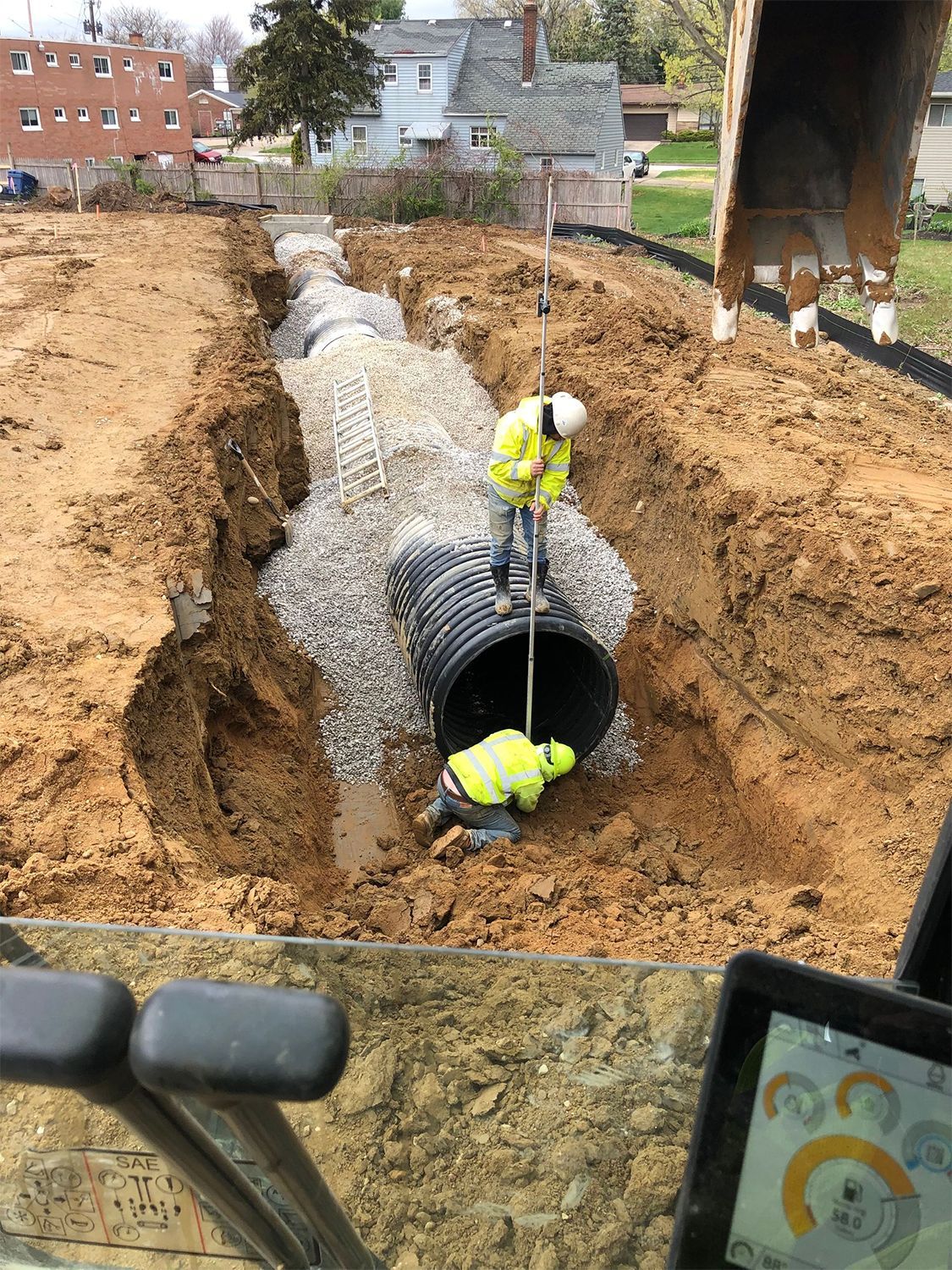 A man is standing in the dirt next to a large pipe.