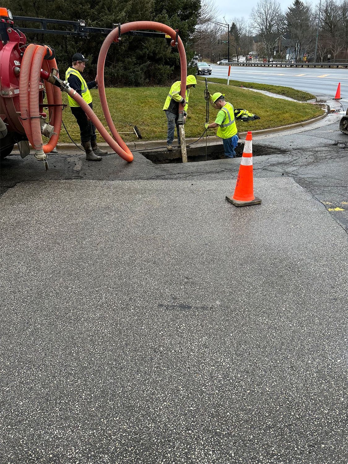 A group of construction workers are working on a hole in the ground.