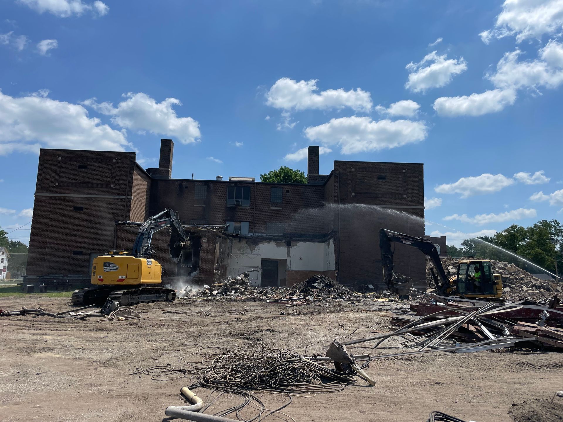 A large brick building is being demolished by a bulldozer.