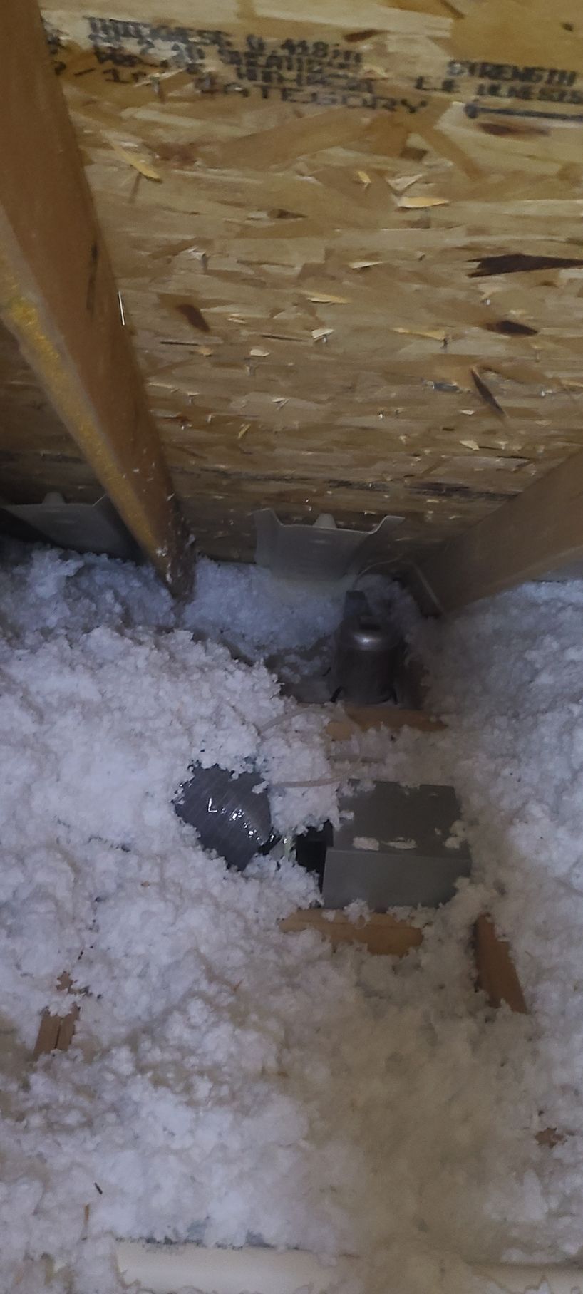 Attic space with insulation around a hole, wooden beams.