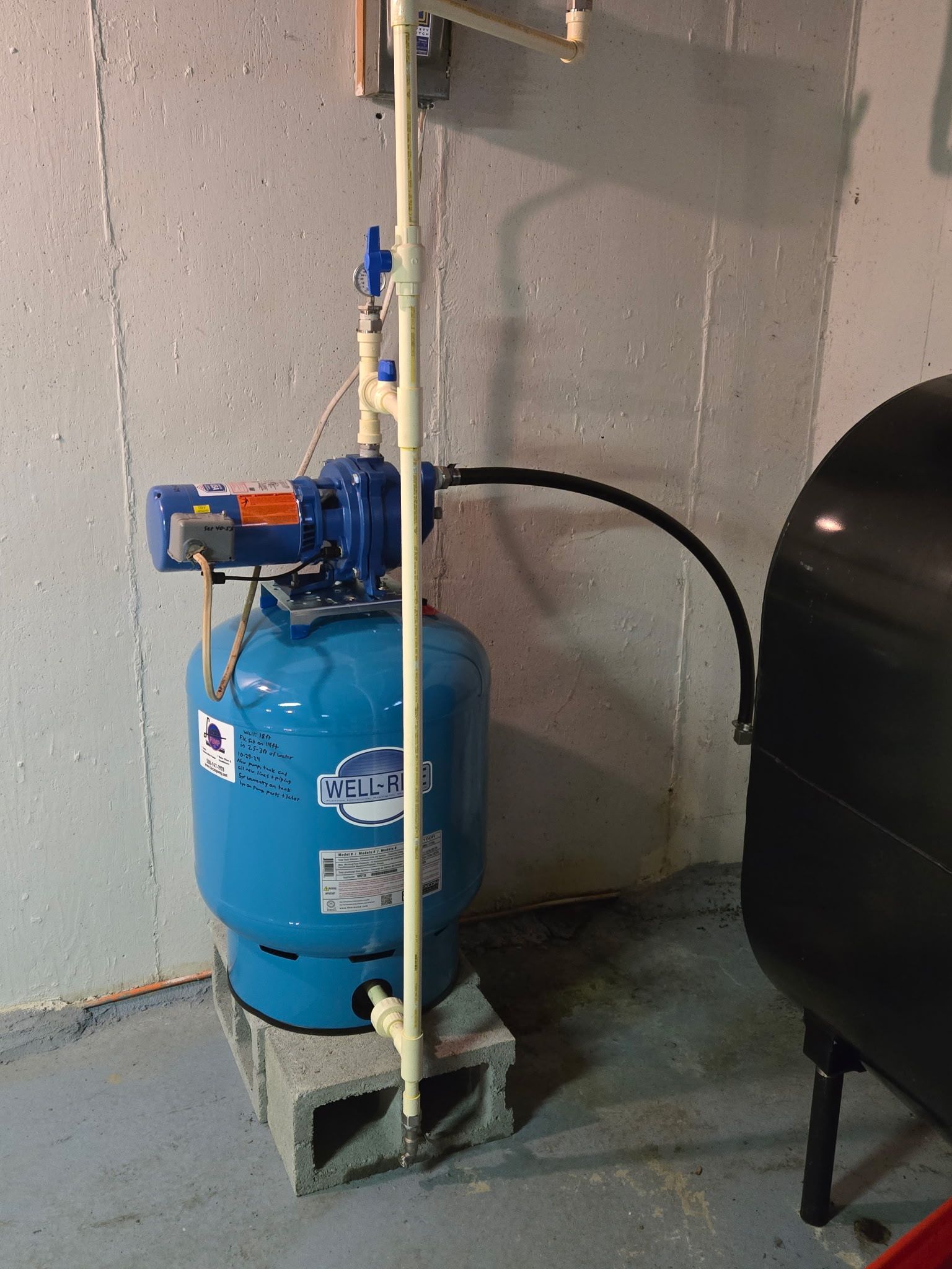 Blue water well tank with pump and plumbing in a basement.