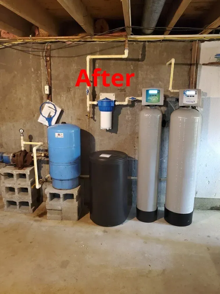 Water filtration system in a basement setting with various tanks, pipes, and digital displays.