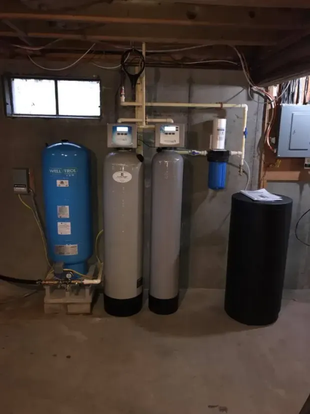 Water filtration system in a basement setting with various tanks and components.