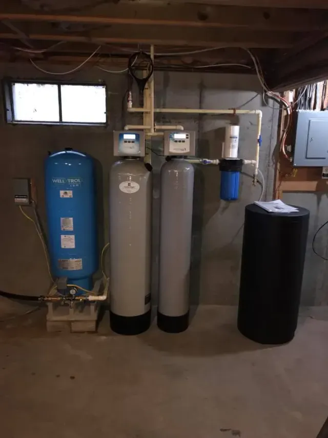 Water filtration system in a basement setting with various tanks and components.