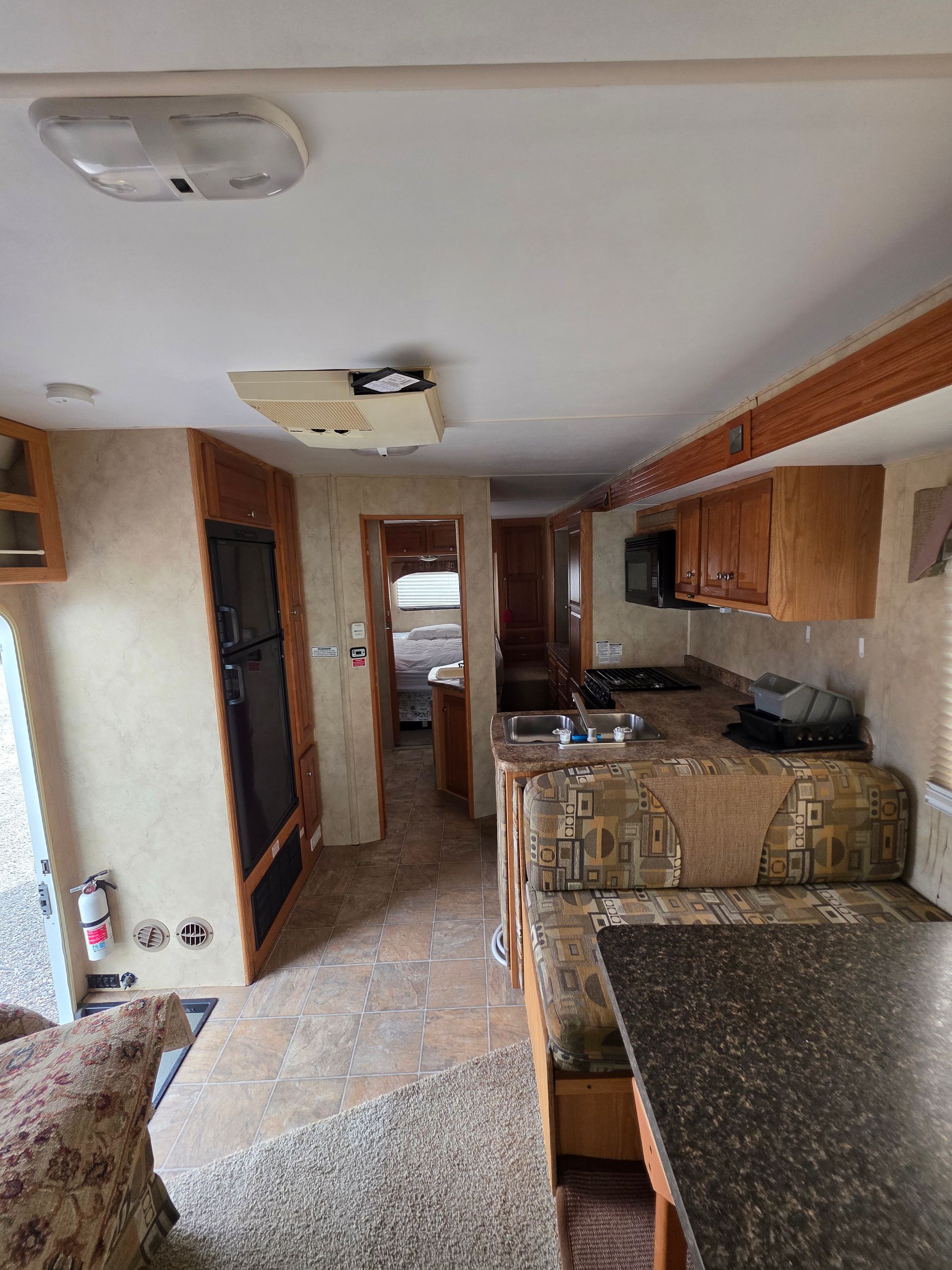 Interior of a camper, showing kitchen, dining area, and hallway to bedroom.