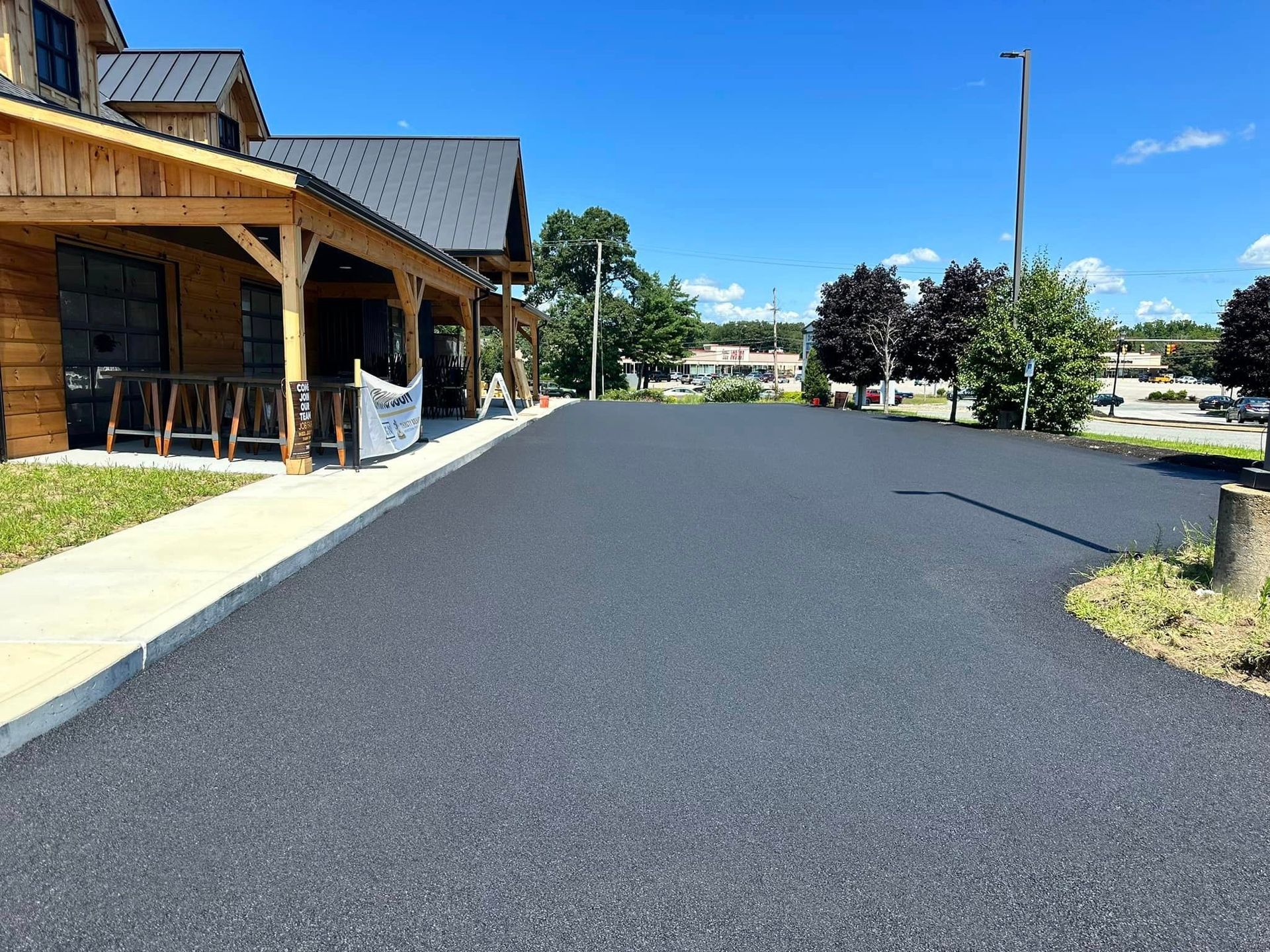 A large asphalt driveway with a wooden building in the background