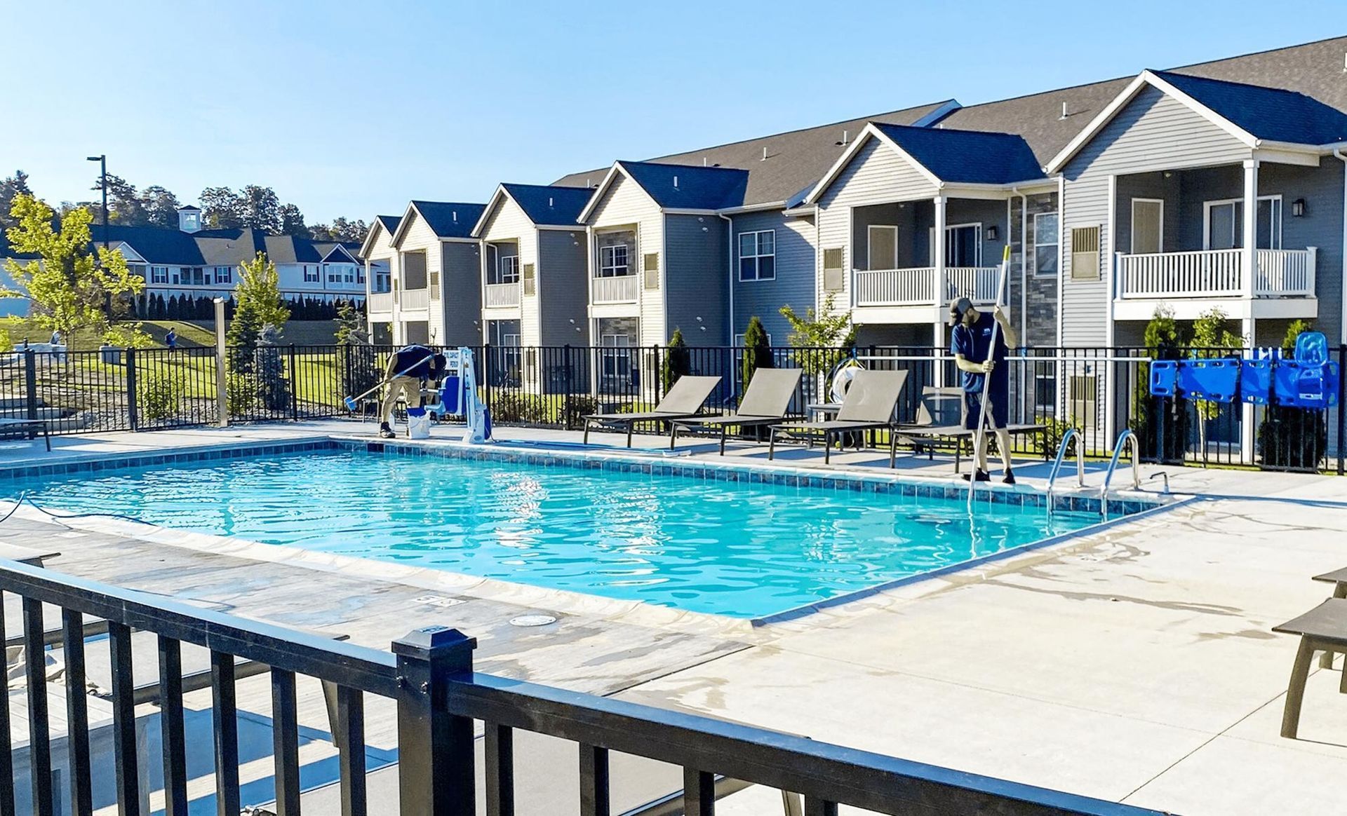 Pool vacuum hose draining water into a swimming pool with a person in the background.