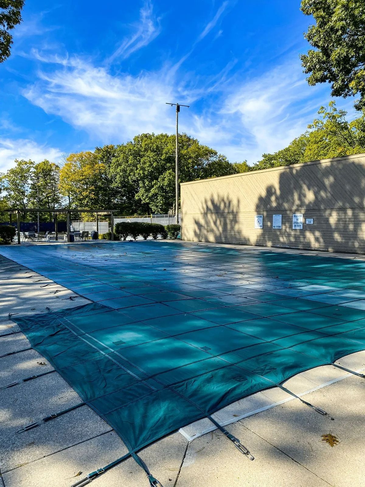 Closed public pool covered with green tarp on a sunny day.
