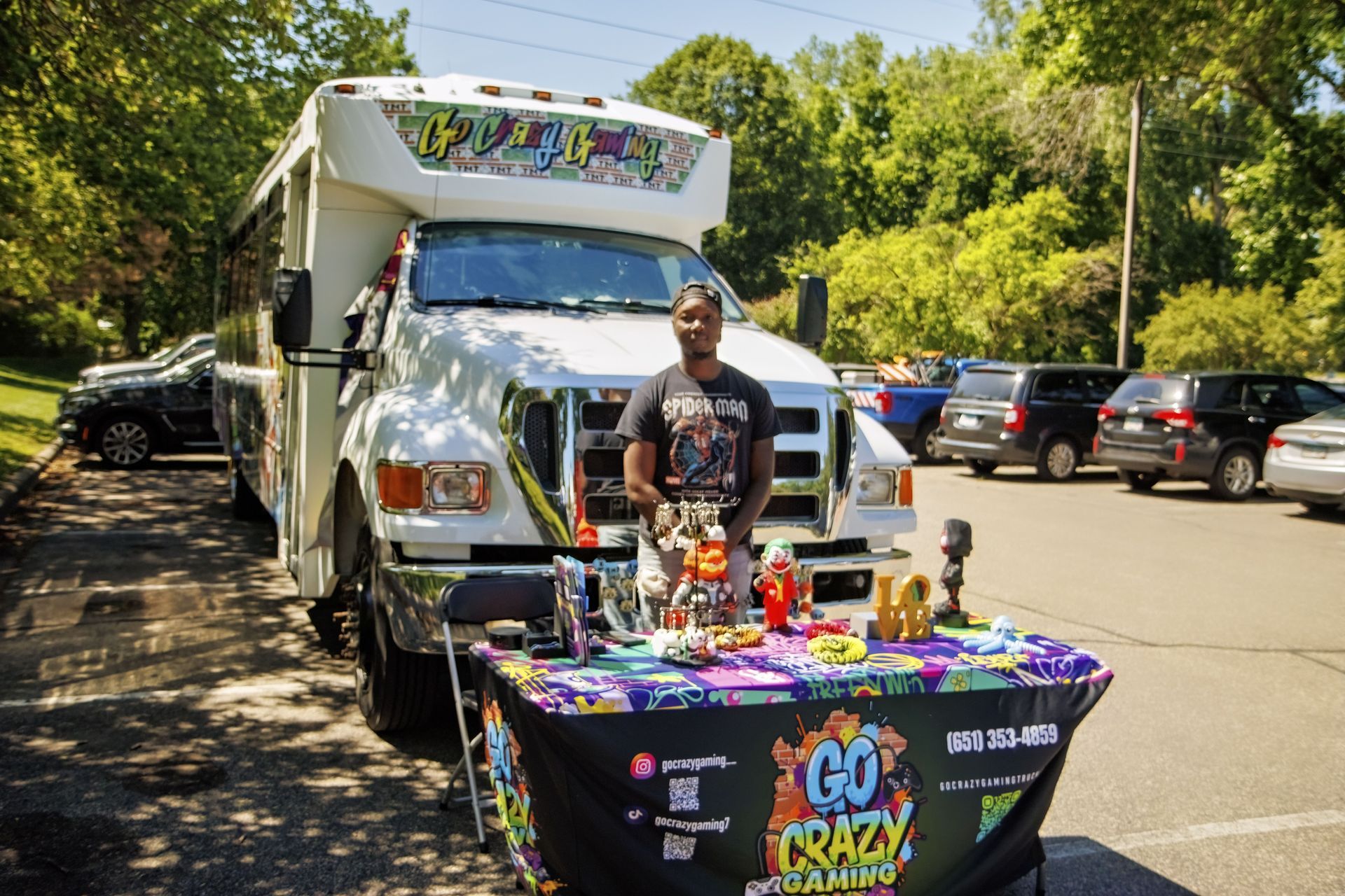 Person at a colorful outdoor vendor booth beside a white truck in a parking lot