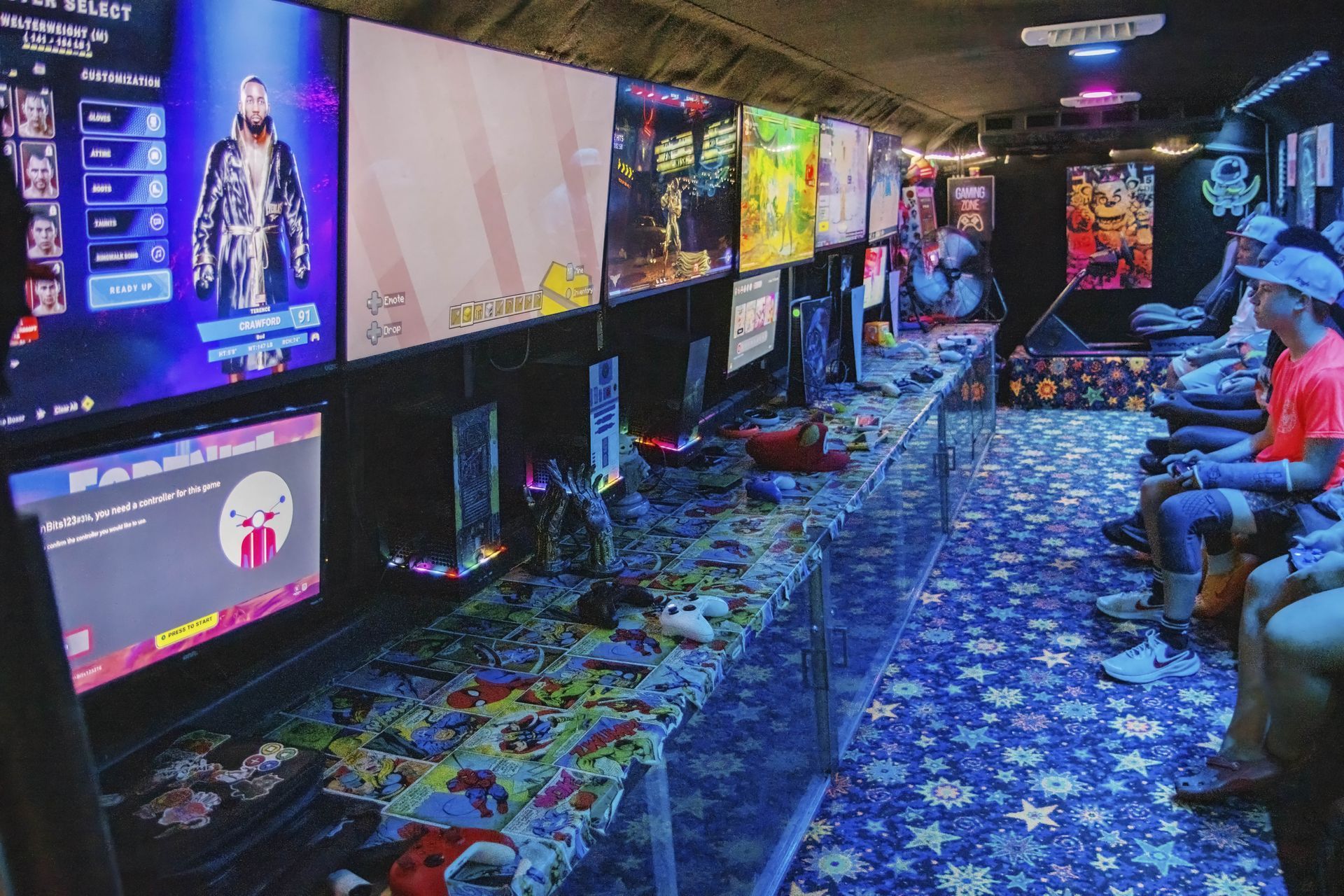Arcade hallway with glowing game screens, neon lights, and people seated along the right side