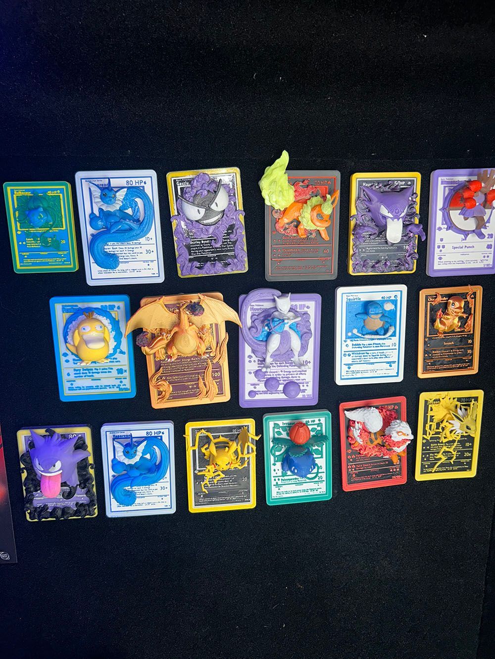 Assorted colorful trading cards arranged in rows on a black surface