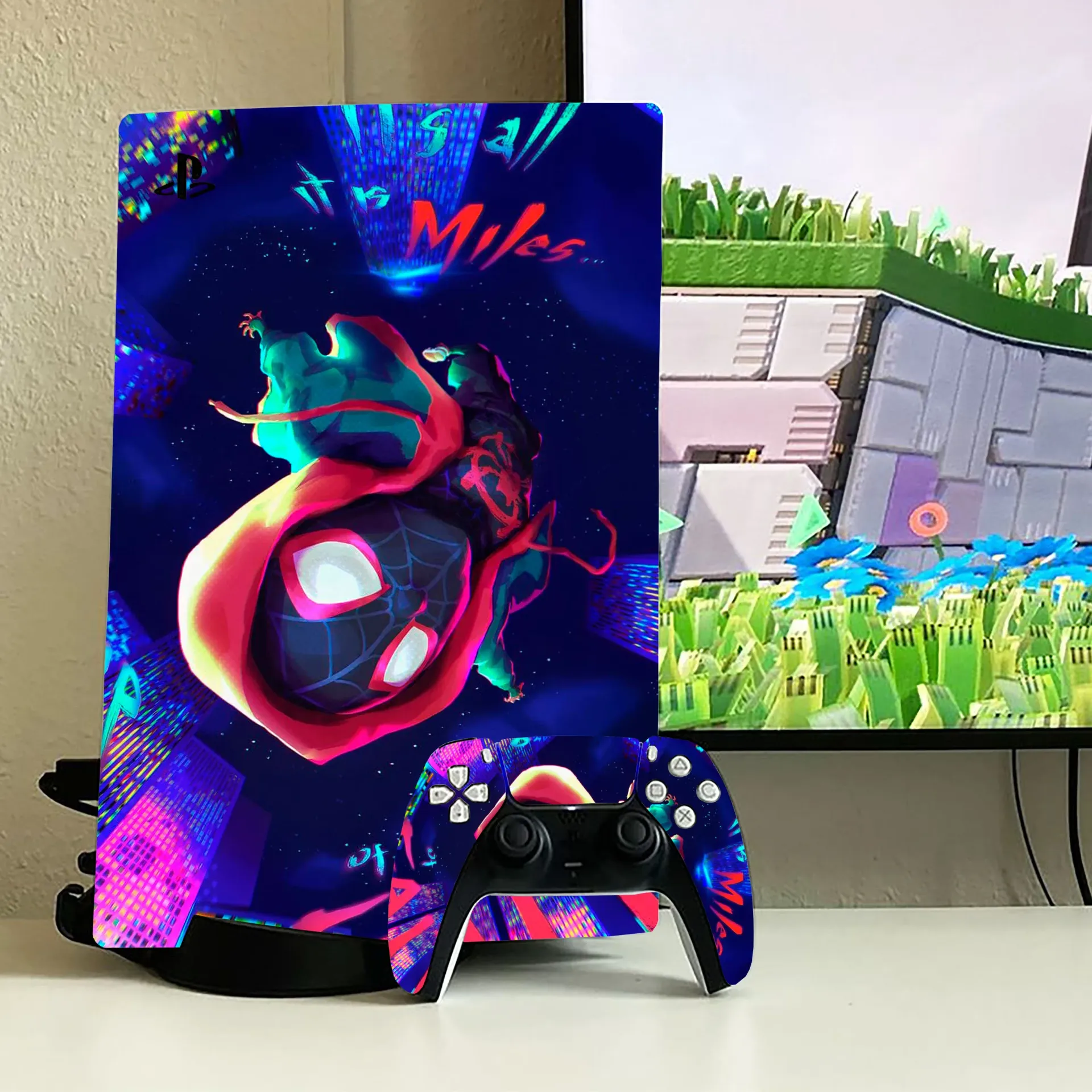 A PlayStation 5 console and controller with a vibrant Miles Morales skin, placed on a white surface in front of a screen.