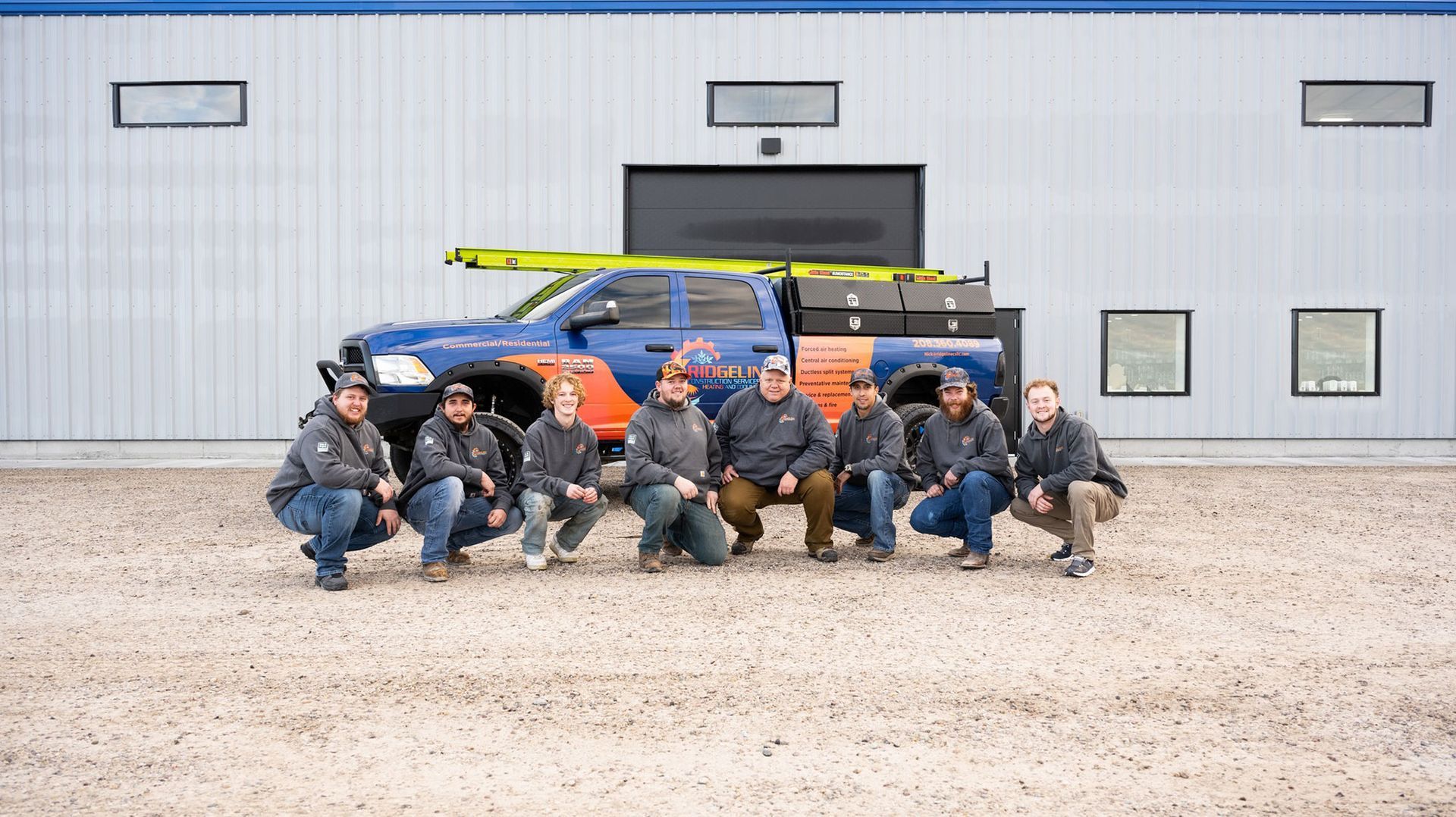 A group of men are posing for a picture in front of a truck.