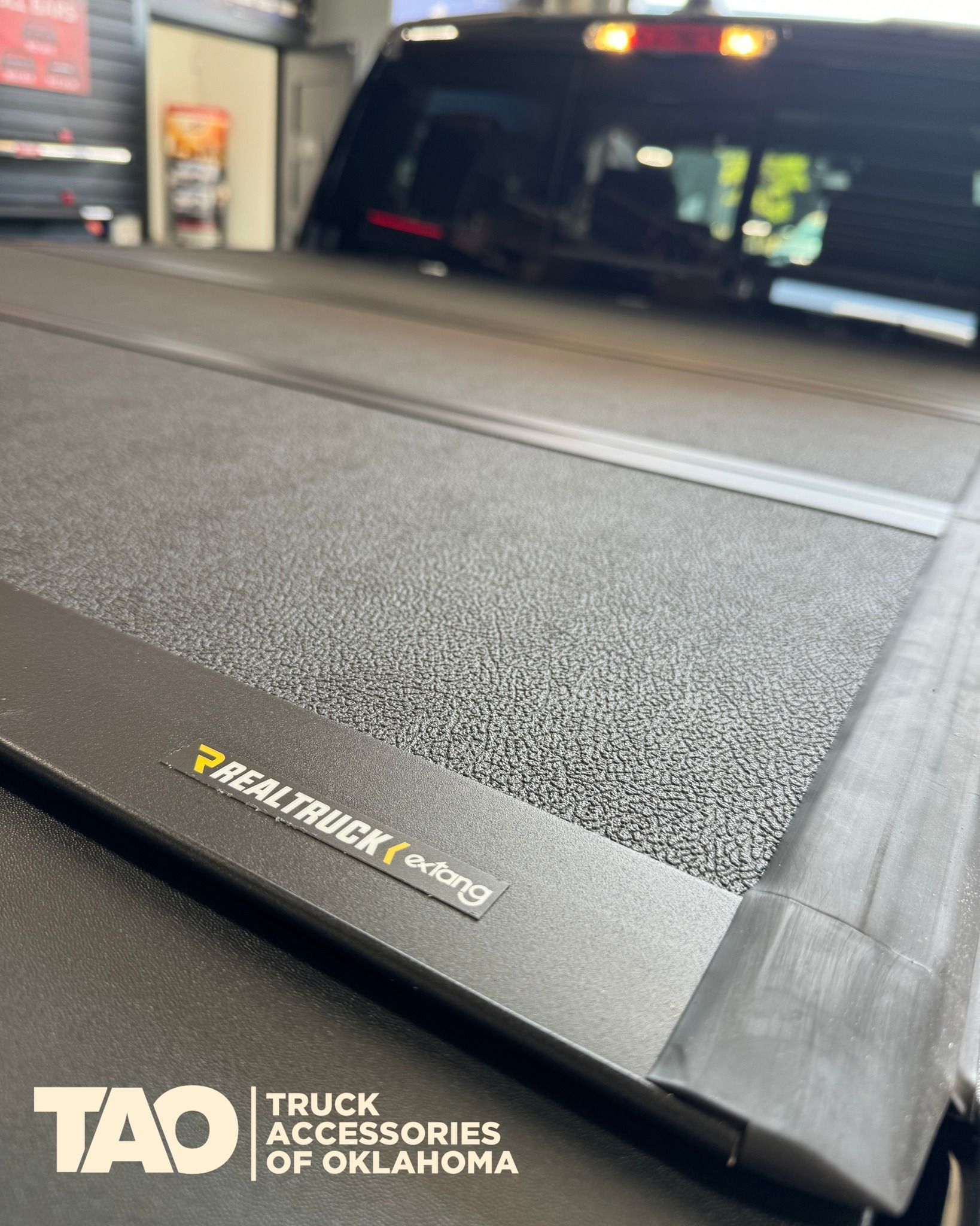 Black truck bed cover with RealTruck logo, in shop.