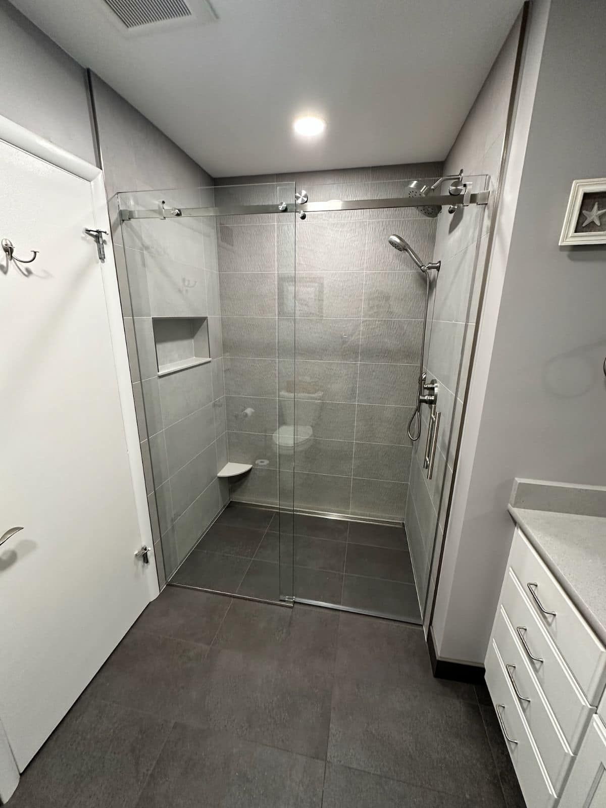 A bathroom with a walk in shower with a glass door.
