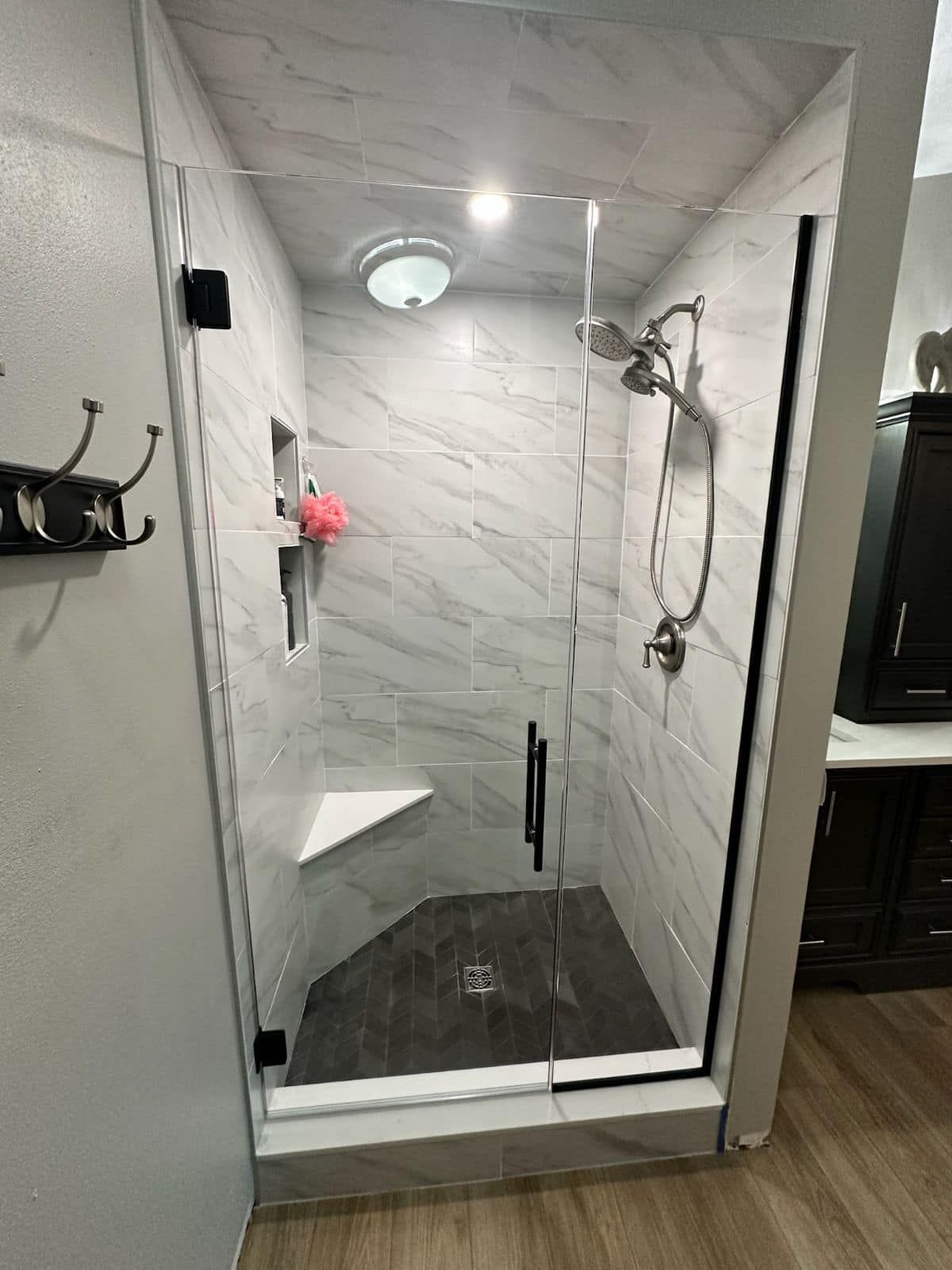 A bathroom with a walk in shower with a glass door.