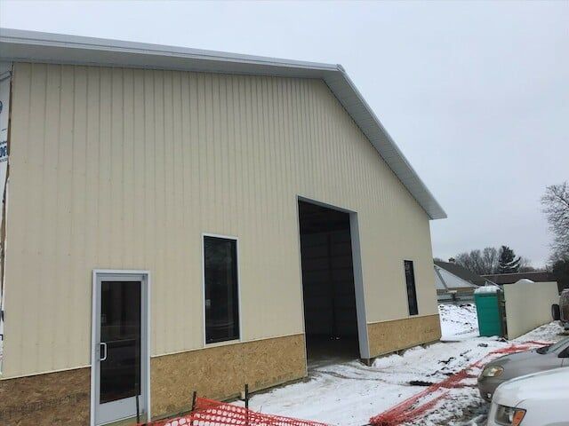 A white building with a large door is being built in the snow.