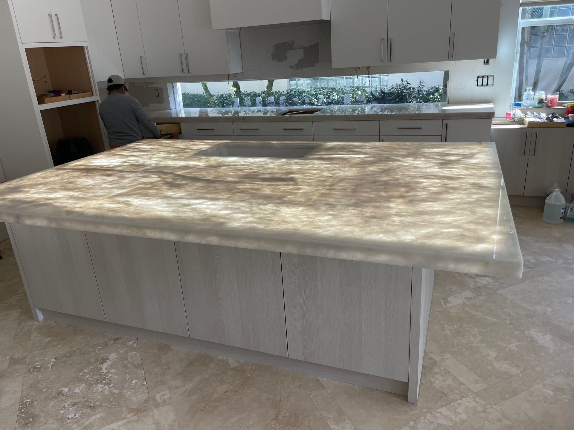 A kitchen with white cabinets and a large island with a marble counter top.